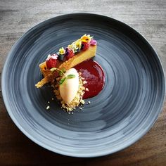 a blue plate topped with a dessert covered in toppings on top of a wooden table