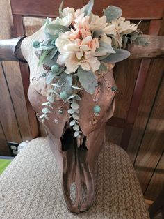 a cow skull with flowers and leaves on it's head sitting on a chair