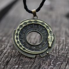 a necklace with an old metal object hanging from it's side on a wooden surface