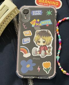 an iphone case with stickers on it sitting next to a string of hair clips