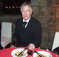 a man in a suit and tie sitting at a table with two plates of food