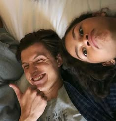 a man and woman laying on top of a bed next to each other with their eyes closed