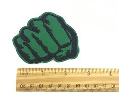 a measuring ruler with a green and black iron - on patch sitting next to it