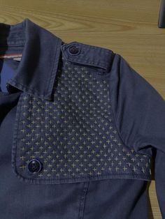 a blue shirt with yellow and black designs on the collar is sitting on a wooden surface