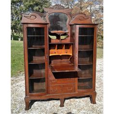 an old wooden bookcase with mirror and drawers on it's sides, in the middle of a gravel area