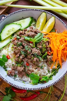 a bowl filled with rice, meat and veggies on top of a wooden table