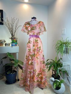 "Vintage 1960/1970's Floral beauty This gorgeous beauty boasts a peach, pink, and orange floral pattern with a lovely purple velvet waist sash. She has an absolutely stunning floral print. Check out her pictures as they speak for themselves.💚 Measurements provided are flat and have been doubled. Bust 34\" Waist 25\" Hips free\" Length 55\" ❤️ Condition: Excellent vintage condition with a newly replaced zipper! This item has been cleaned and is ready to wear. $143 includes domestic shipping and 1970s Spring Vintage Dress, 70s Floral Dress, 1970s Maxi Dress With Vintage Print, Maxi Dress 70s, 1970s Style Floor-length Maxi Dress, 1970s Floral Beach Dresses, Her Pictures, Heart Blouse, 1970s Floral Print Maxi Dress