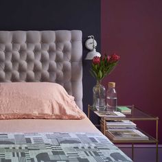 a bed with pink sheets and pillows next to a vase filled with flowers on a side table