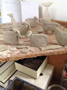 several clay sculptures sitting on top of a wooden table next to books and other items