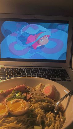 an open laptop computer sitting on top of a desk next to a plate of food