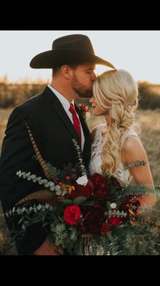 a man in a cowboy hat kissing a woman with long blonde hair and red flowers