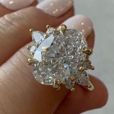 a woman's hand holding a diamond ring with three pear shaped diamonds on it