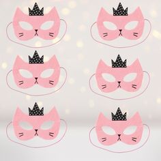 four pink masks with black crowns on them, one has a cat's face and the other has a polka dot crown