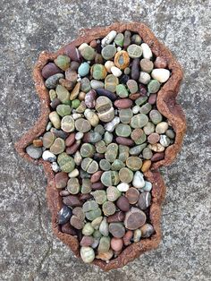 a pot filled with lots of rocks on top of a cement floor next to a sidewalk