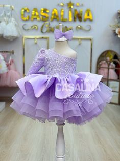 Watch your daughter light up with joy as she steps into the enchanting world of the Malinda Dress in Lilac Purple. This mesmerizing garment is tailor-made for baby girls who deserve to revel in elegance and charm. The Malinda Dress, with its graceful long train, promises to transform your little one into a fairy-tale princess with every wear. In a delightful shade of Lilac Purple, this knee-length dress features a voluminous skirt, creating a playful and spirited silhouette. The upper bodice of Purple Easter Dress, Lavender Flower Girl, Lavender Flower Girl Dress, Dress For Baby Girl, Purple Easter, Dress Glitter, Dress Lavender, Dress Lilac