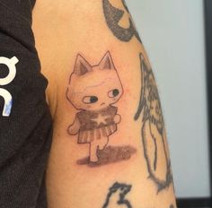 a person with a cat tattoo on their arm and shoulder, holding a small teddy bear