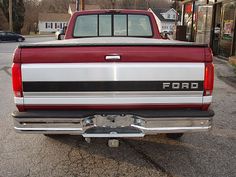 the rear end of a red truck parked in a parking lot