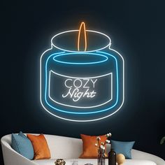 a lit candle sitting on top of a white couch next to a wall with the words cozy night