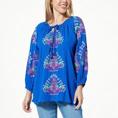 One World Embroidered Top Bursts of bold embroidery extend its way up to the center of this flowing blouse with billowy sleeves. Finished with a tasseled tie, it adds rich color and effortless style to any look. Blue Bohemian Printed Peasant Top, Blue Bohemian Top With Tassel Ties, Blue Bohemian Tops With Tassel Ties, Bohemian Blue Tops With Tassel Ties, Casual Blue Tops With Tassel Ties, Bohemian Blue Top With Blouson Sleeves, Blue Tunic Tops For Fall, Bohemian Blue Top With Tassels, Casual Tunic Top With Tassels