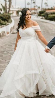 a bride and groom hold hands while walking down the street in front of palm trees