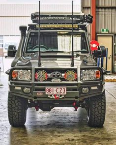 the front end of a vehicle with lights on in a garage area, and another vehicle behind it