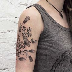 a woman's arm with flowers and leaves on the left side of her arm