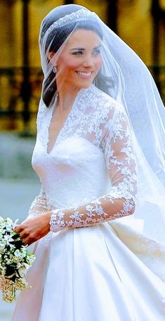 the bride smiles as she walks down the street in her wedding dress and veil,