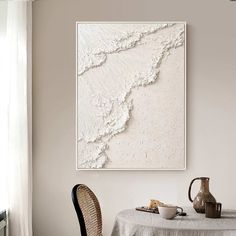 a dining room table with two chairs and a painting hanging on the wall above it