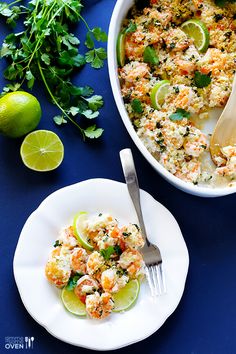 a bowl of shrimp salad next to a plate with limes and parsley on the side