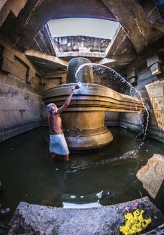 a man standing in the water near a fountain