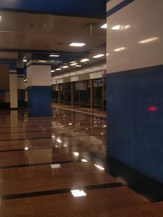 an empty lobby with blue walls and tile flooring in the middle, at night