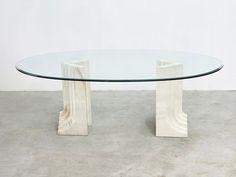 a glass table with two white pedestals on the top and one in the middle