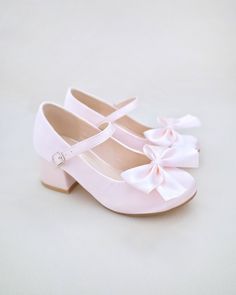 a pair of pink shoes with a bow on the front and bottom, sitting on a white surface