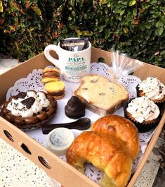 a box filled with different types of pastries next to a cupcake and coffee