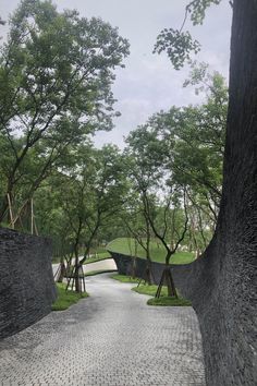 the walkway is lined with trees and cobblestone roads that lead to an open grassy area