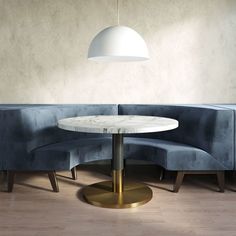 a round table sitting in the middle of a room next to a blue couch with a white lamp hanging above it