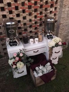 two small tables with flowers and candles on them in front of a brick wall,