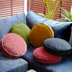 four pillows on a blue couch in front of a window