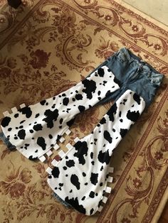 two pairs of jeans with black and white cow print on them sitting on the floor