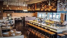 the inside of a restaurant with lots of tables and chairs in front of it, along with bar stools