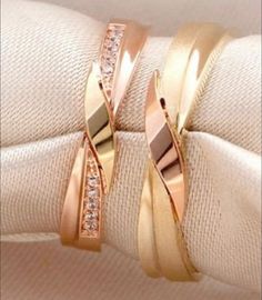 two gold rings sitting on top of each other next to white napkins and cloth