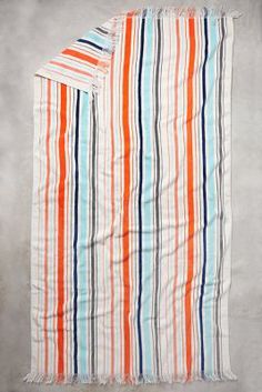 an orange, blue and white striped towel on a gray surface with a black stripe