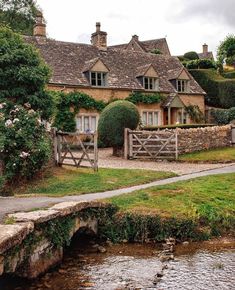 a stone house sitting next to a small stream in front of it's entrance