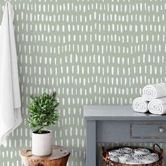 a bathroom with green and white wallpaper, a potted plant and two towels