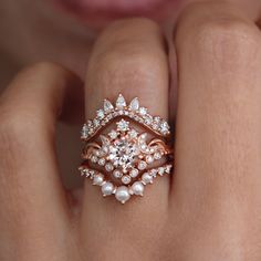 a close up of a person's hand wearing a ring with pearls and diamonds