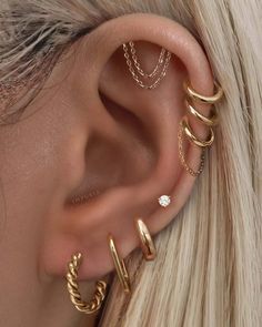 a woman with blonde hair wearing three different ear piercings and one has a diamond in the middle