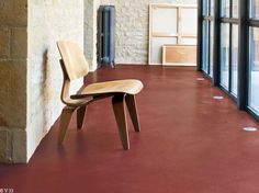 a wooden chair sitting on top of a red floor next to a wall and windows