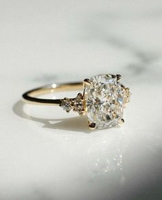 an oval diamond ring with three small diamonds on the side, sitting on a white surface