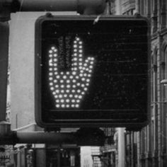 a black and white photo of a street sign with a hand on it's side