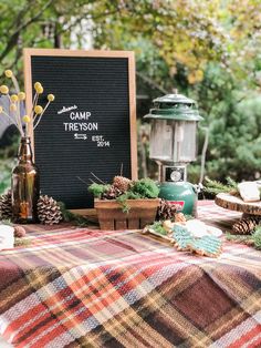 a picnic table with pine cones, candles and other items on it is set up for an outdoor party